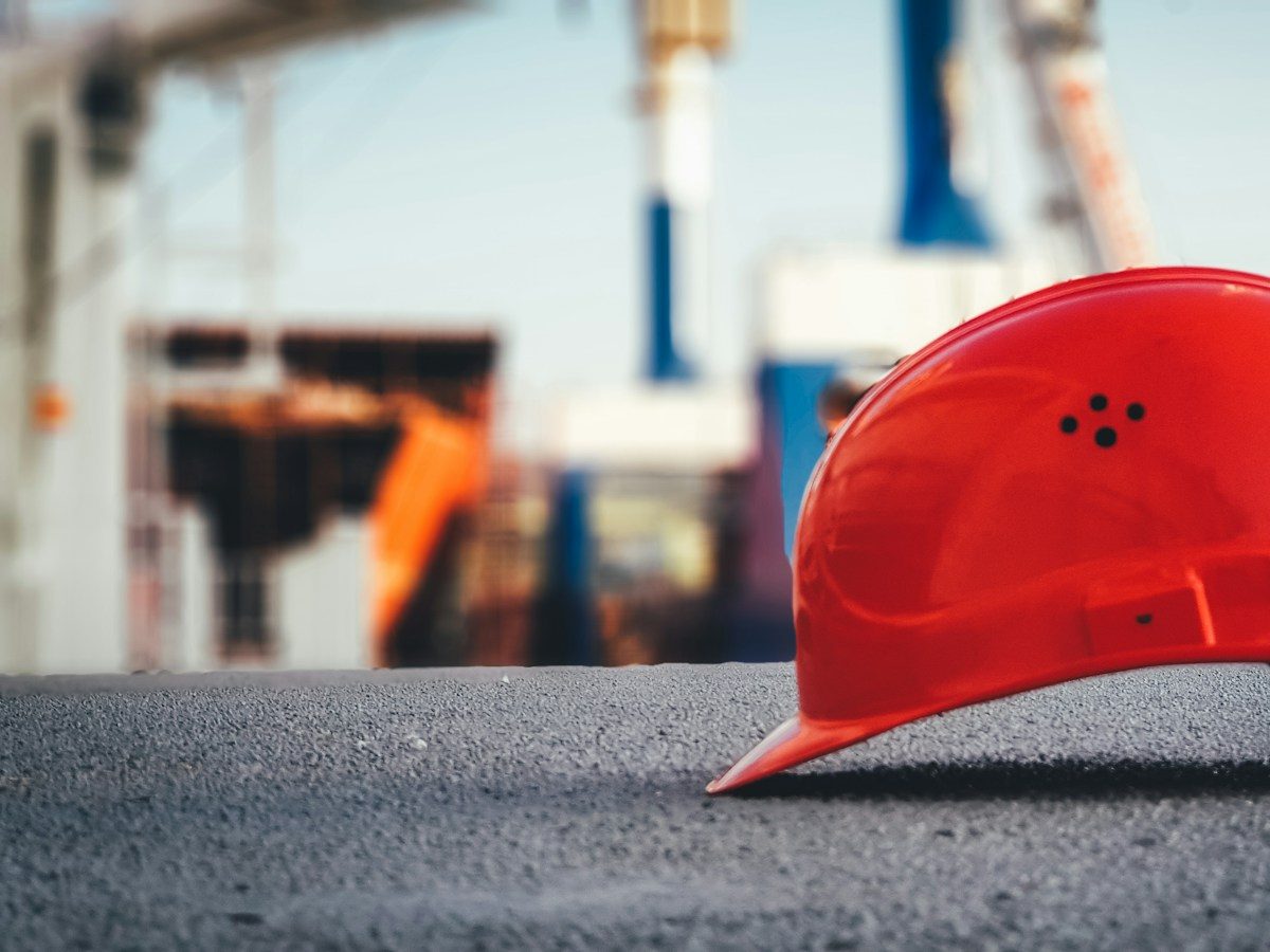 A red hard hat resting on pavement