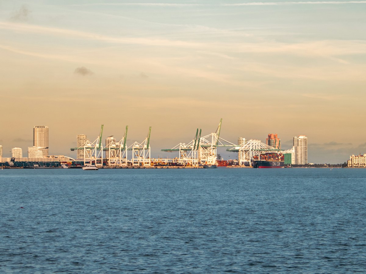 Container cranes of a busy port on the far side of a bay at sunset
