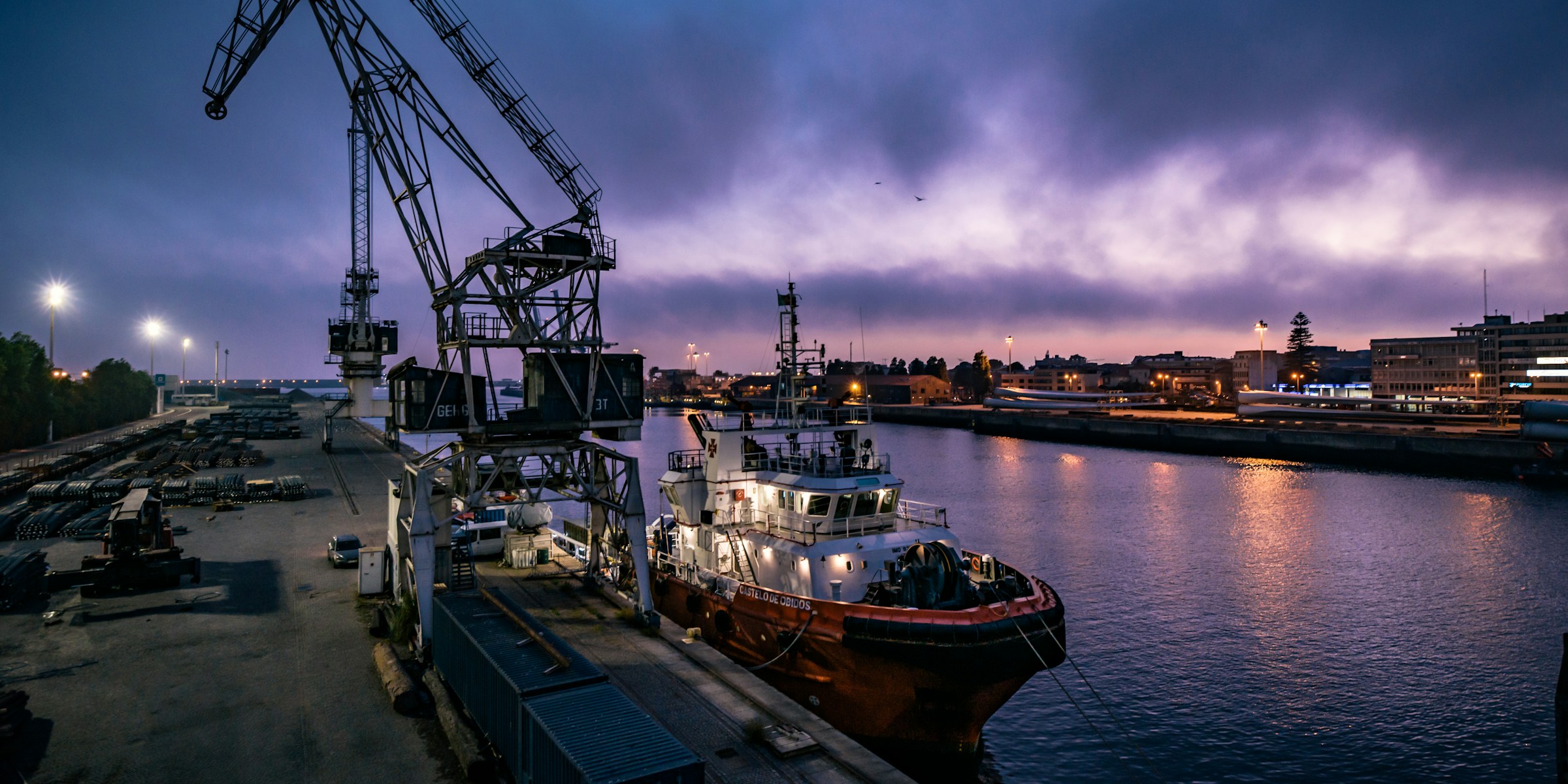 A tug alongside a lit quay at dusk